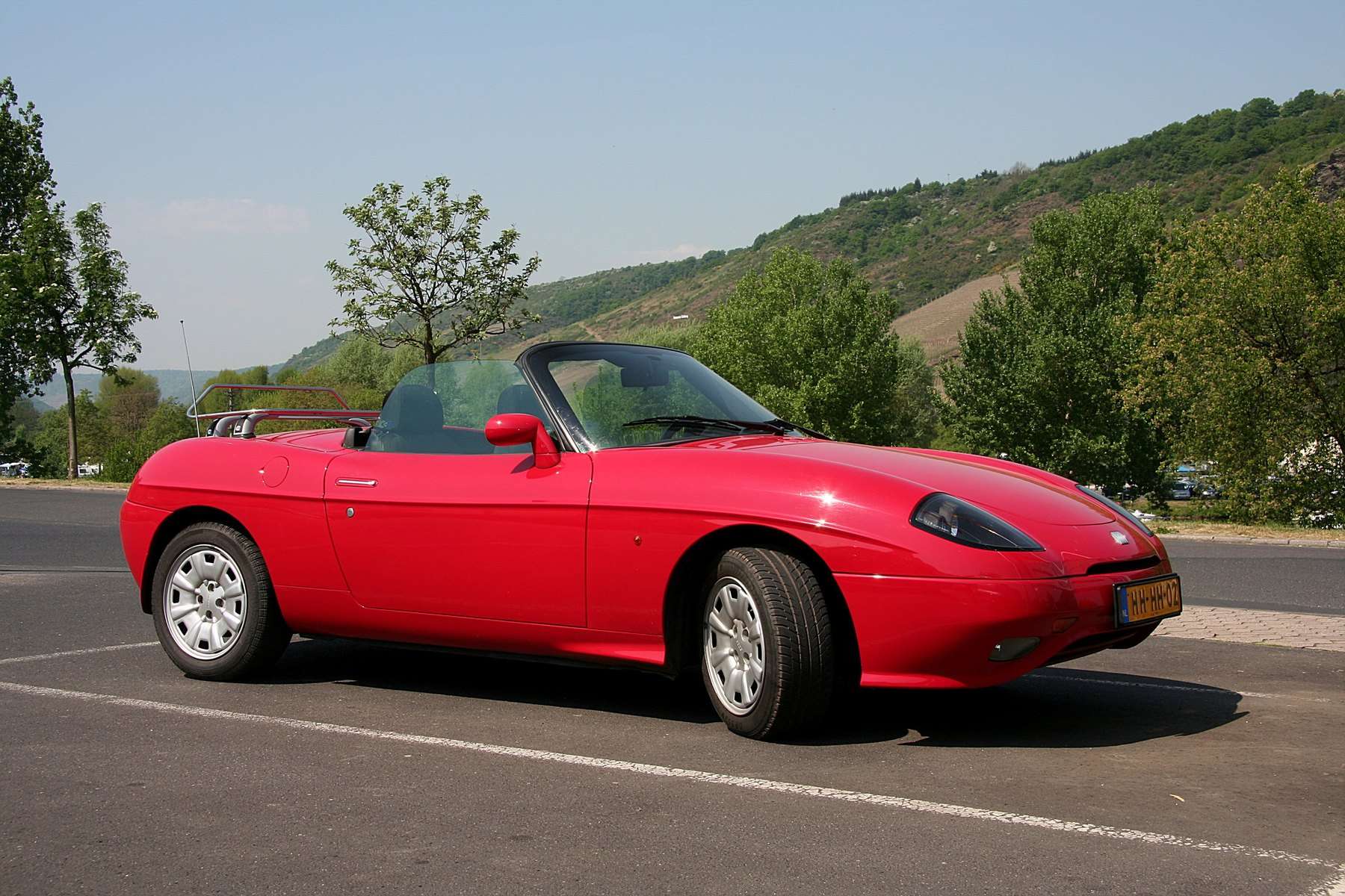 Red Fiat Barchetta in side profile with the roof lowered